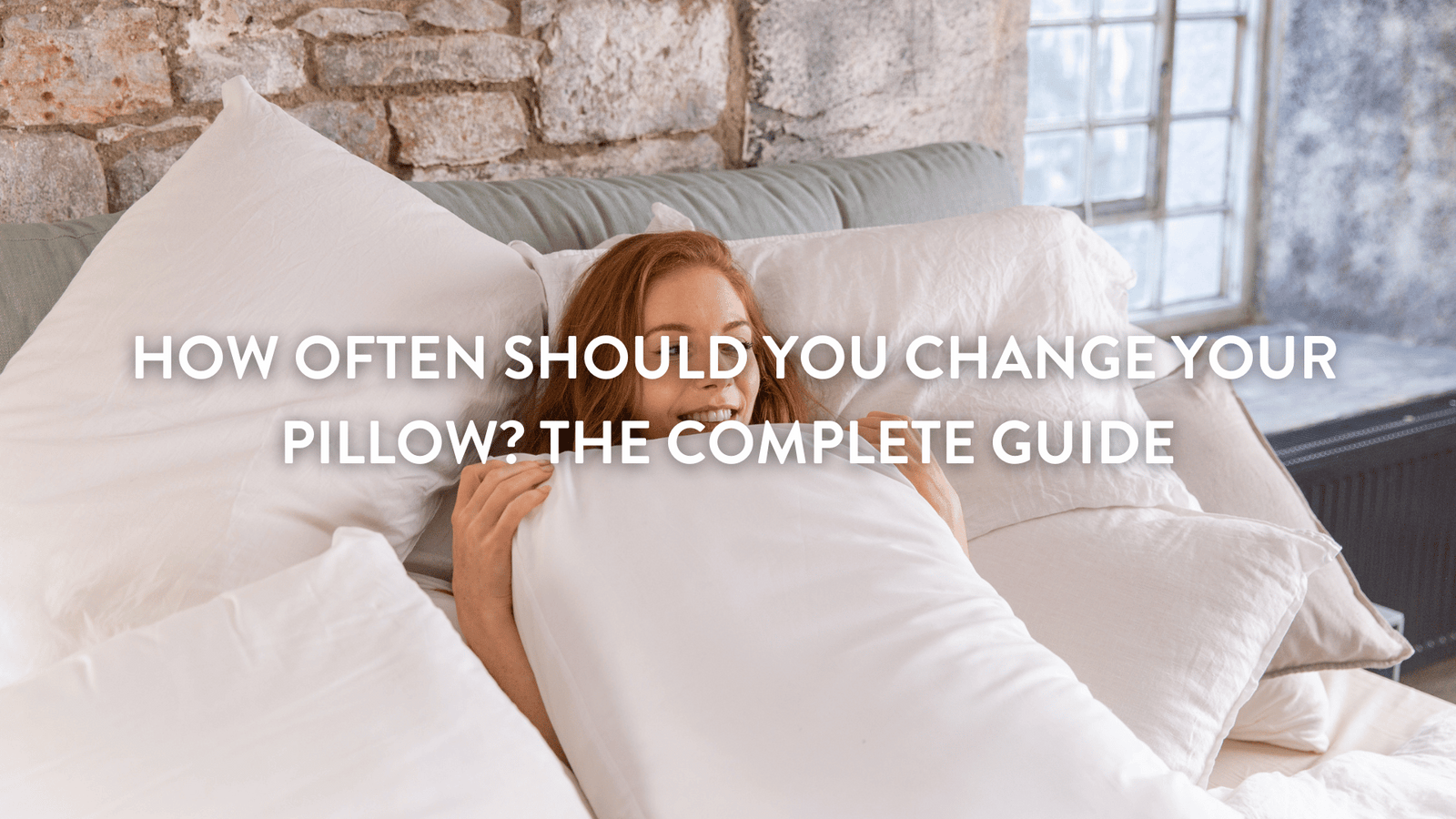 person in bed holding a pillow in front of them