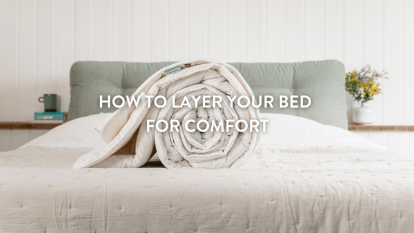 Rolled up Putnams Duvet on top of a white bed with a teal cushioned headboard